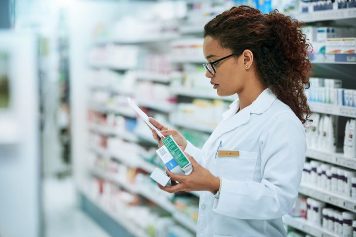 Young pharmacist filling out a prescription while working in a chemist