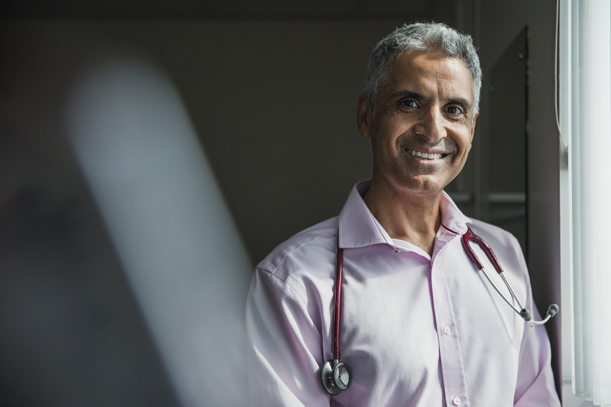 Portrait of a mature Asian doctor smiling at the camera.